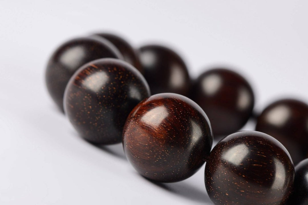 A close-up of deep red sandalwood prayer beads with spiritual energy, showcasing the natural grain and patina of this sacred wood from Lydazz.