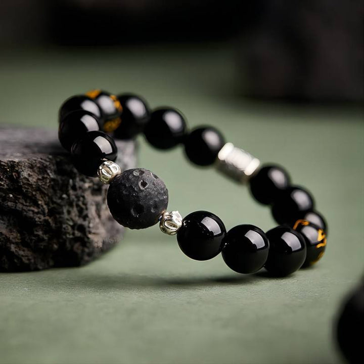 Grounded Mantra Bracelet - Side view prop styling shot of black obsidian bracelet with obsidian meteorite bead