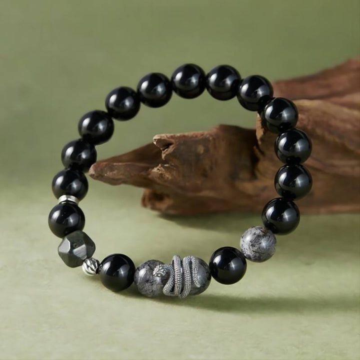 Mamba Serpent Charm Bracelet - Vitality &amp; Grounding - Side view prop styling shot of black obsidian bracelet