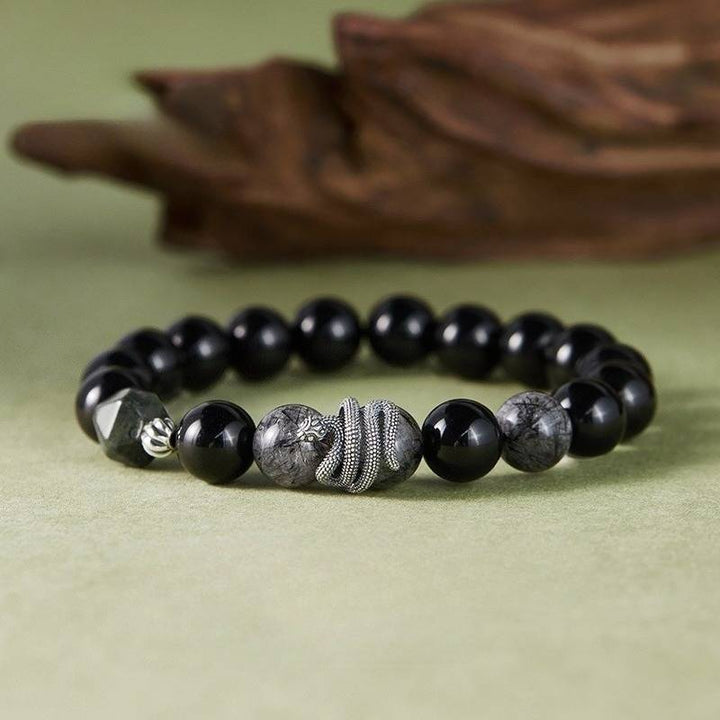 Mamba Serpent Charm Bracelet - Vitality &amp; Grounding - Front view prop styling shot of black obsidian bracelet
