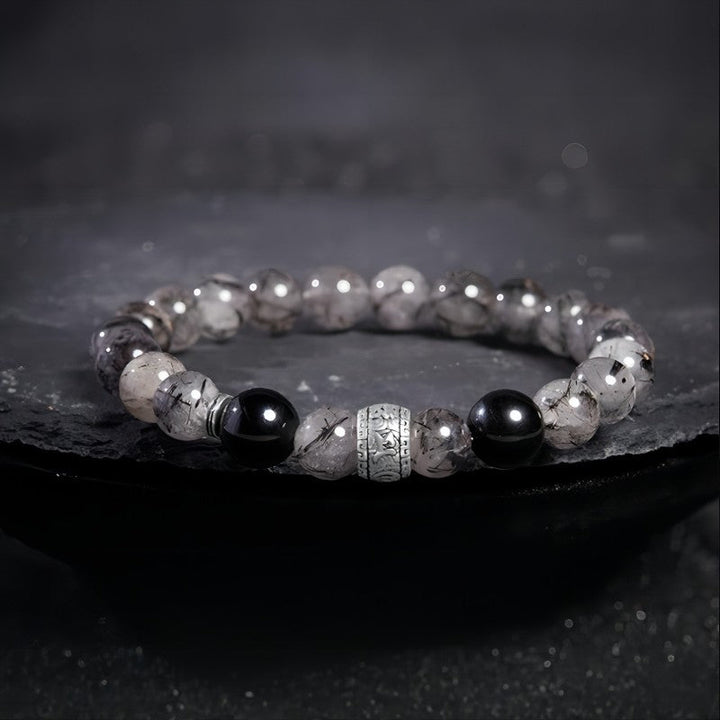Protection Mantra Bracelet - Abundance &amp; Clarity - Prop styling shot of black obsidian and sliver bracelet